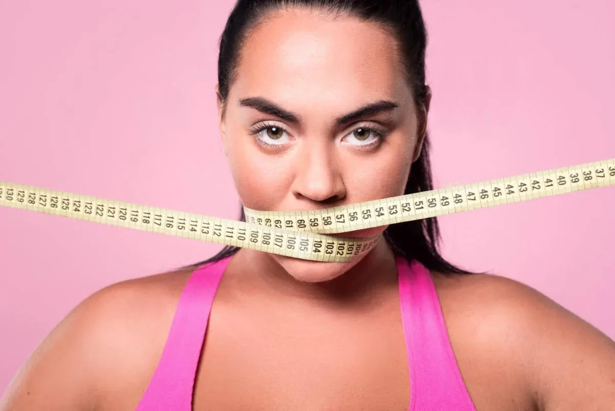 stop eating close up portrait of chubby mulatto lady covering her mouth with body measuring tape jpg webp